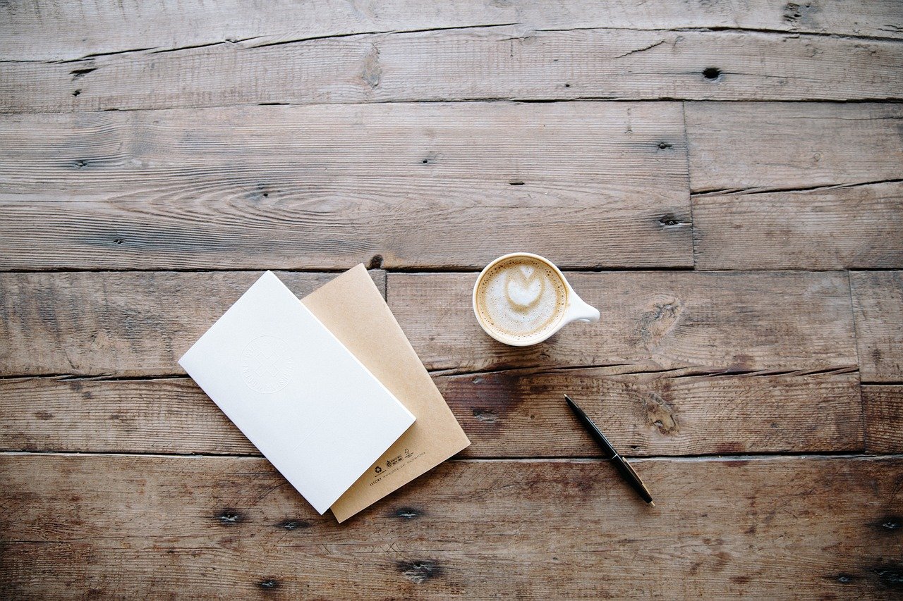 a memo pad and a cup of coffee on wooden table