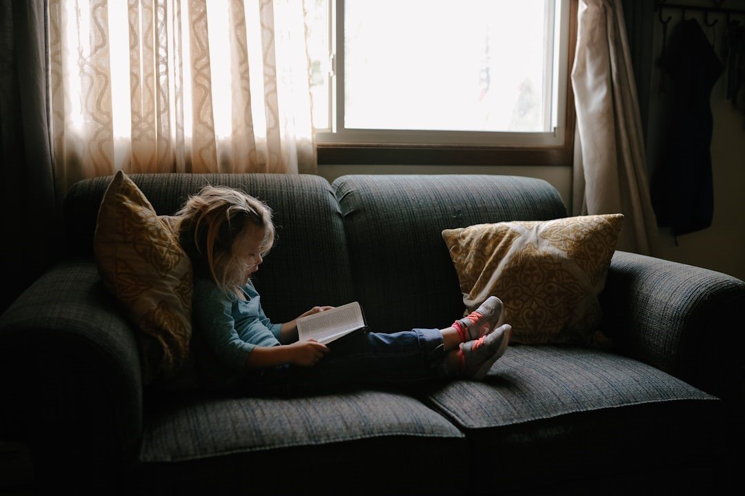 A girl is reading a book on a sofa