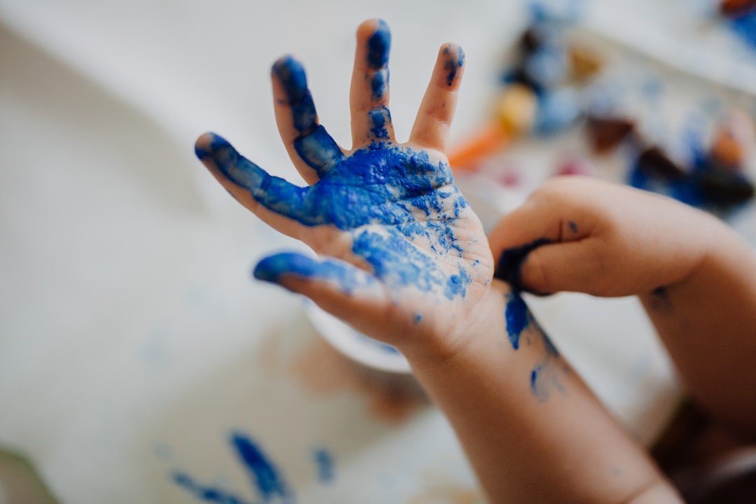 A child's hand is covered with blue paint