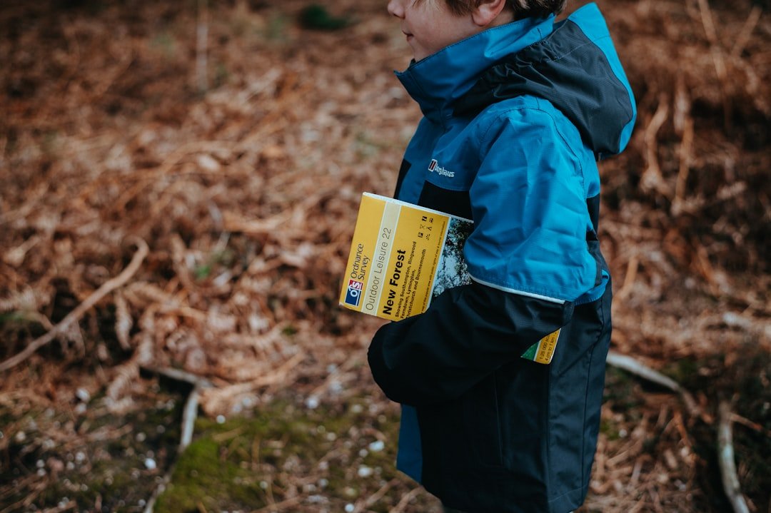 A boy with a map walking inside forest.