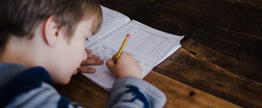 A boy is studying on a wooden desk