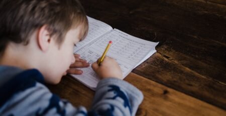 A boy is studying on a wooden desk