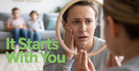 A mom looking at a mirror and two children sitting on couch at the background